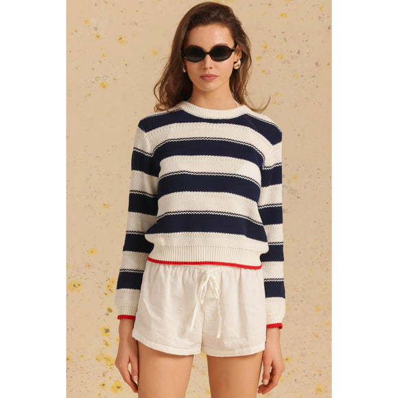 Woman wearing a striped sweater and white shorts on a beige background