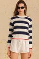 Woman wearing a striped sweater and white shorts on a beige background