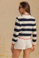 Woman wearing a navy and white striped sweater with a beige background
