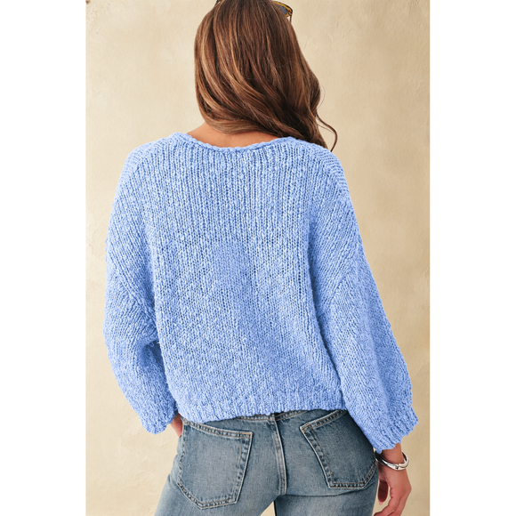 Person wearing a light blue sweater and jeans against a beige background
