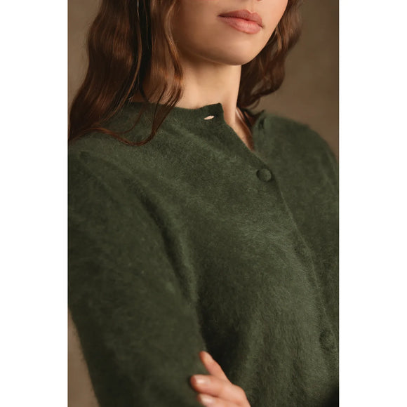 Close-up of a woman wearing a soft, fuzzy dark green cardigan sweater with a buttoned neckline.