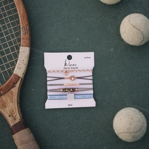 Vintage tennis racket and balls on a green surface with a Klanc hair ties packaging.