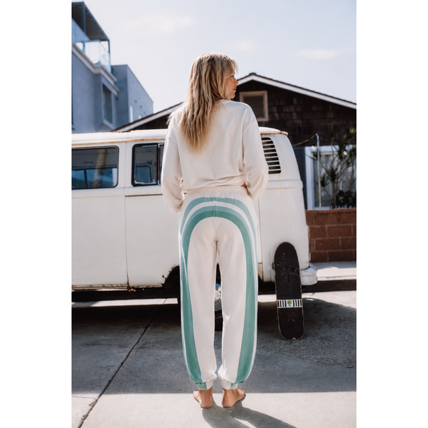 Woman wearing a white outfit with green stripes standing in front of a white van.