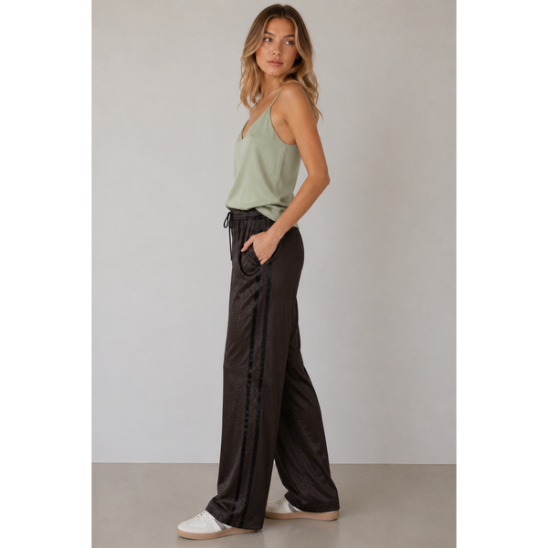 Woman wearing a green top and black wide-leg pants against a plain background
