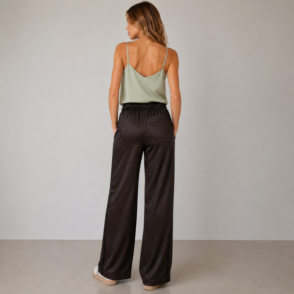 Woman wearing a light green top and dark pants against a plain background