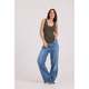 A woman modeling a sleeveless olive green tank top and wide-leg blue jeans against a plain light gray studio background.