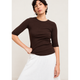 A woman modeling a dark brown 3/4-sleeve crewneck top and dark navy wide-leg trousers, standing against a plain light beige wall.