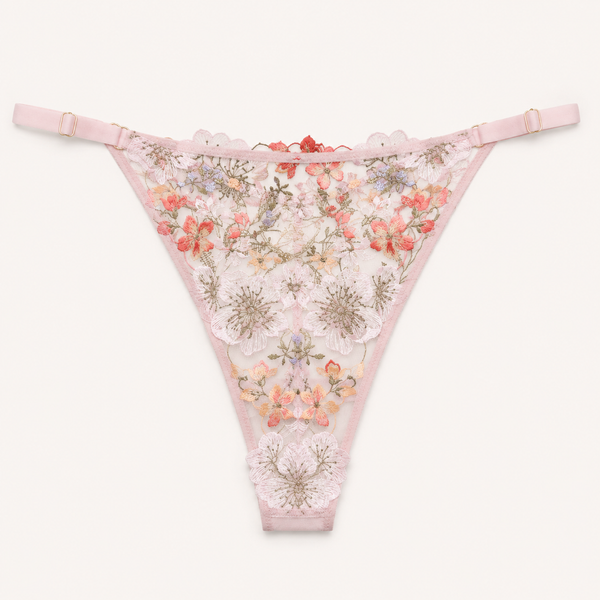 Light pink lace thong panties with floral embroidery and a scalloped edge, displayed flat against a light off-white background.