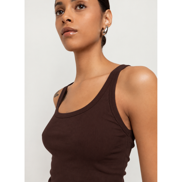 A close-up shot of a model wearing a dark brown ribbed tank top against a light gray background.