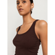 A close-up shot of a model wearing a dark brown ribbed tank top against a light gray background.