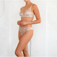 Woman wearing a white lace bra and panties set on a plain background