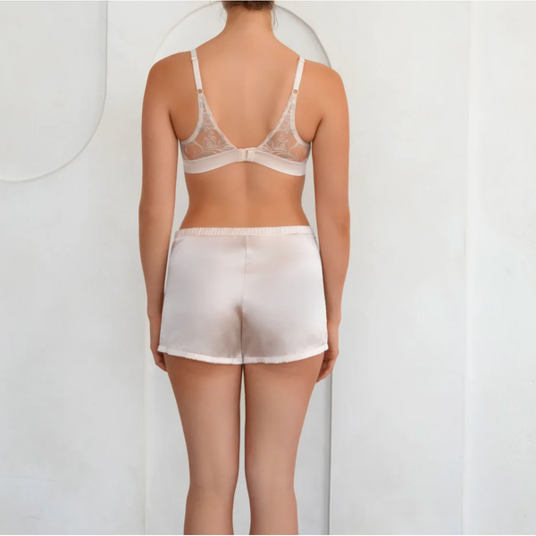 Person wearing a sheer light pink  bra and shorts set on a plain background