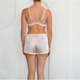 Person wearing a sheer light pink  bra and shorts set on a plain background