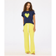 Woman wearing a navy t-shirt with a yellow heart and yellow pants on a white background