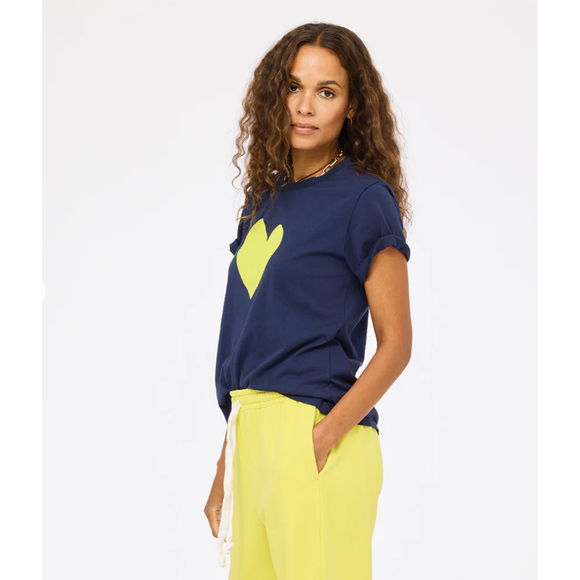 Woman wearing a navy blue t-shirt with a yellow heart design and yellow pants on a white background