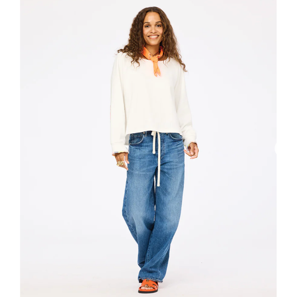Woman wearing a white sweater and blue jeans on a white background