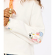 Close-up of a white garment with colorful sleeve designs on a plain background