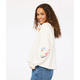 Woman wearing a white sweatshirt with colorful designs on a plain background