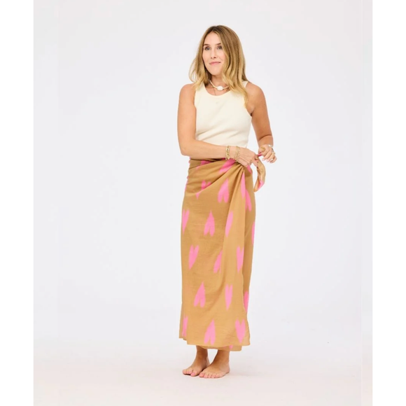 Woman wearing a beige sleeveless top and pink patterned skirt on a white background
