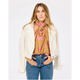 Woman wearing a beige jacket, pink blouse, and blue jeans on a white background