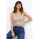 Woman wearing a beige tank top and blue jeans against a white background
