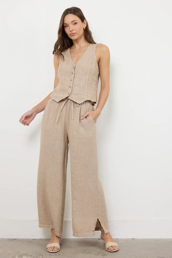 Woman wearing a beige sleeveless top and wide-leg pants against a white background