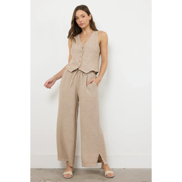 Woman wearing a beige sleeveless top and wide-leg pants against a white background