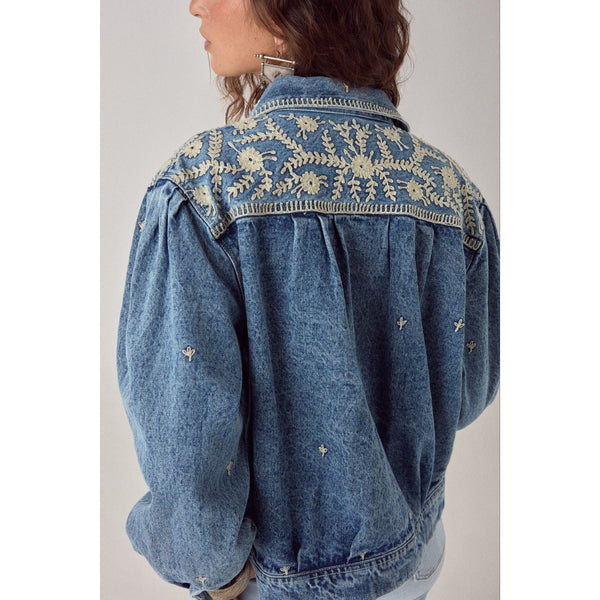 Denim jacket with floral embroidery on a plain background