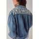 Denim jacket with floral embroidery on a plain background