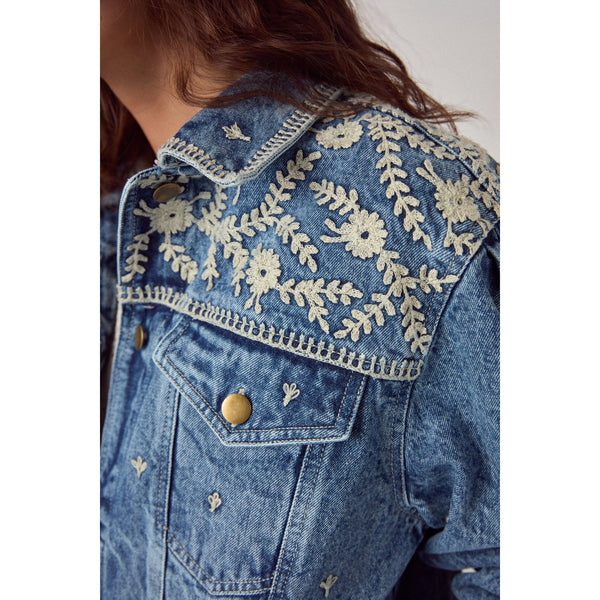 Denim jacket with intricate white embroidery on a plain background