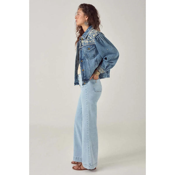 Person wearing a denim jacket and jeans on a plain background