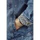 Close-up of a blue denim jacket with embroidered cuffs and a gold bracelet.