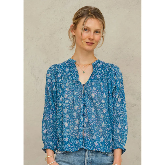 Woman wearing a blue floral blouse against a plain background