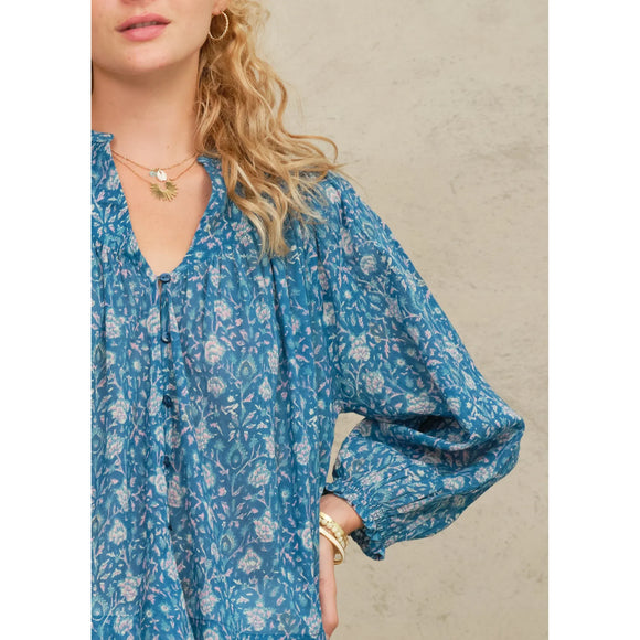 Woman wearing a blue floral dress with a neutral background