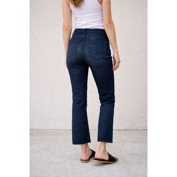 Person wearing dark blue jeans and a white top on a light gray background