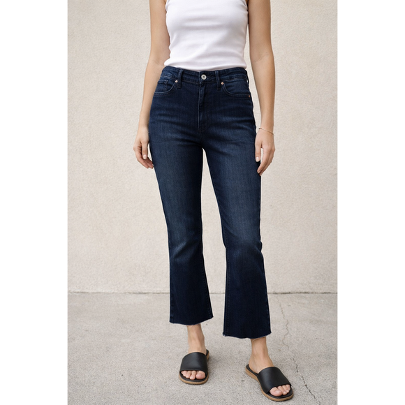 Person wearing dark blue jeans and a white top on a light background