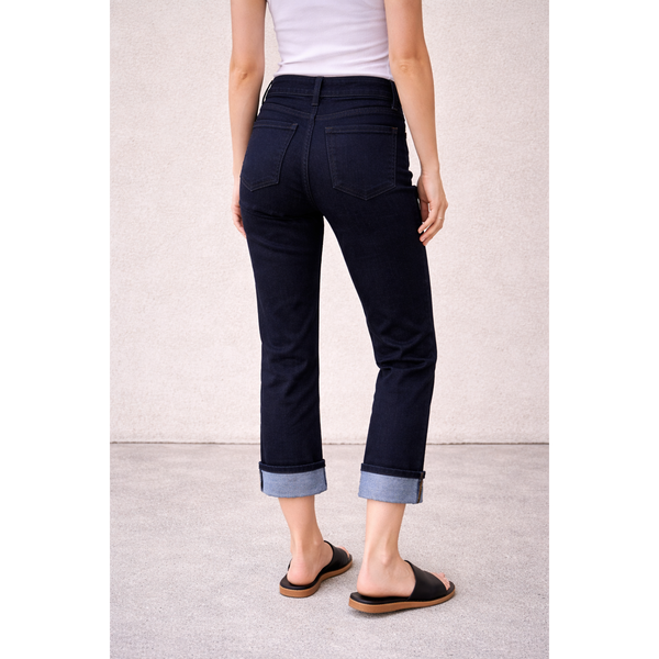 Person wearing navy pants with rolled-up cuffs on a light background