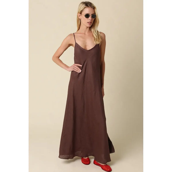 Woman wearing a brown slip dress with red shoes on a beige background