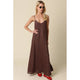 Woman wearing a brown slip dress with red shoes on a beige background