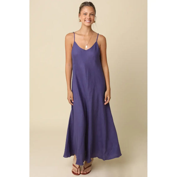 Woman wearing a purple slip dress against a beige background