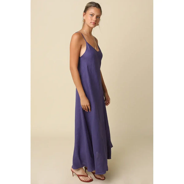 Woman wearing a long purple dress against a beige background