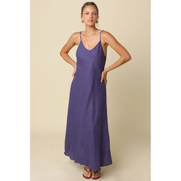 Woman wearing a long purple dress against a beige background