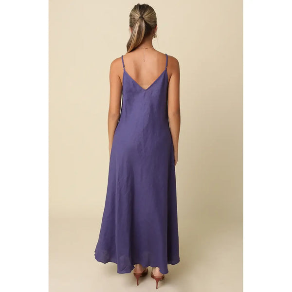Woman wearing a purple slip dress against a beige background