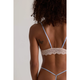 Person wearing a light blue lace bra and panties set against a neutral background