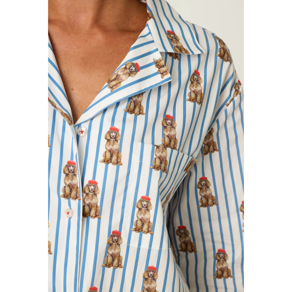 Close-up of a person wearing a collared button-front shirt with blue vertical stripes and an allover print of brown poodles wearing red berets.