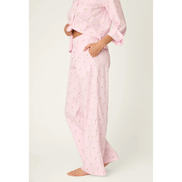 A model wearing a light pink two-piece pajama set with a small green leaf pattern, featuring a long-sleeve button-up top and matching wide-leg pants.
