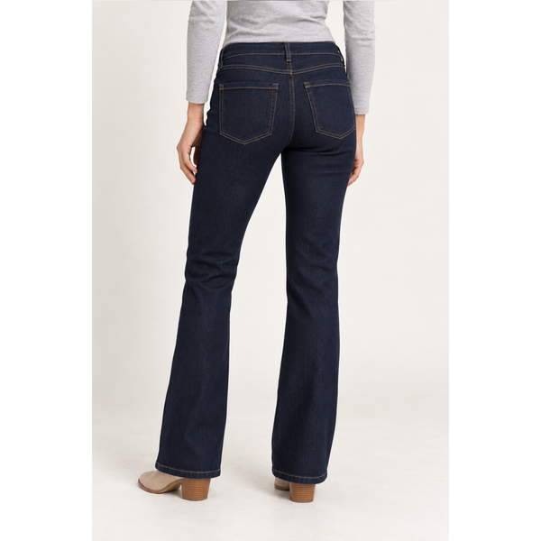 Rear view of a person wearing dark blue flare jeans with a light gray long-sleeve top and beige heeled shoes, photographed against a plain light background.
