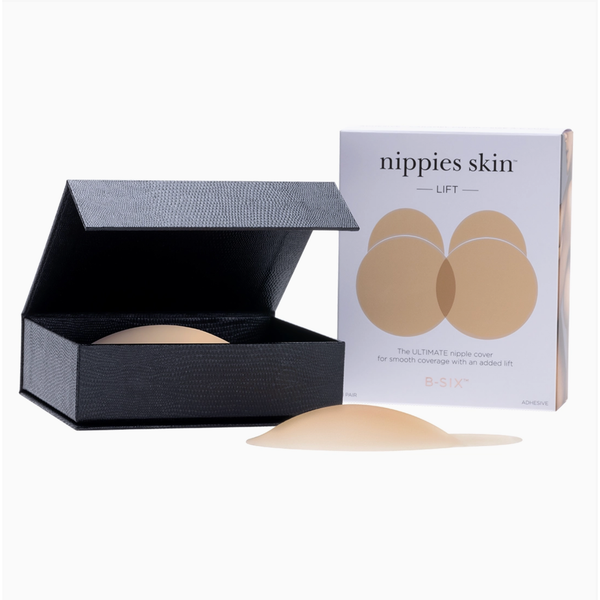 A beige silicone nipple cover shown open in a black textured presentation box, with its retail box standing behind it on a clean white background. The front of the box reads 'nipples skin LIFT' and shows two beige nipple shapes.