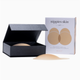 A beige silicone nipple cover shown open in a black textured presentation box, with its retail box standing behind it on a clean white background. The front of the box reads 'nipples skin LIFT' and shows two beige nipple shapes.