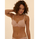 A woman wearing a light beige lace-trimmed bralette and matching underwear, photographed against a plain warm beige studio background.